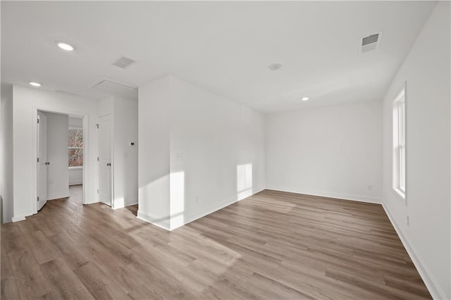 spare room with attic access, recessed lighting, wood finished floors, and visible vents