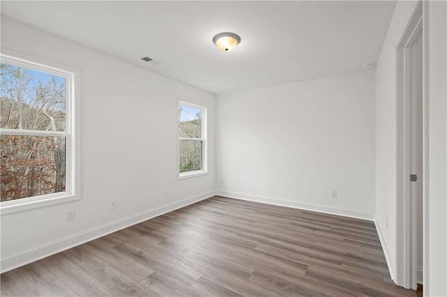 empty room featuring visible vents, baseboards, and wood finished floors