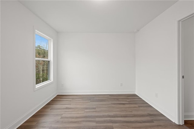 spare room with baseboards and wood finished floors