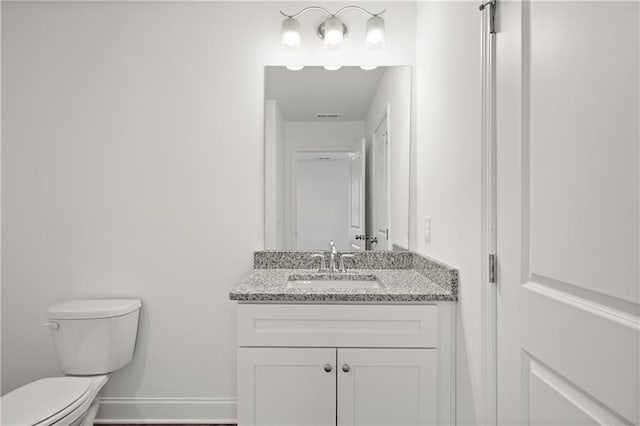 bathroom featuring vanity, toilet, visible vents, and baseboards