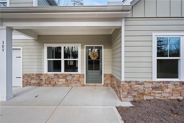 doorway to property featuring board and batten siding and stone siding