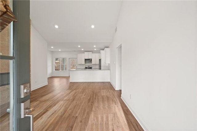 unfurnished living room with recessed lighting, visible vents, baseboards, and light wood finished floors