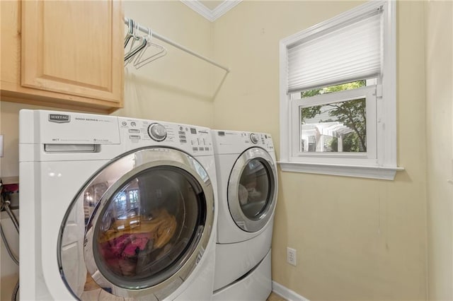 clothes washing area featuring cabinets, crown molding, and washer and dryer