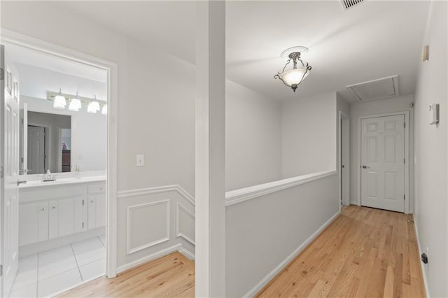 corridor with sink and light hardwood / wood-style flooring