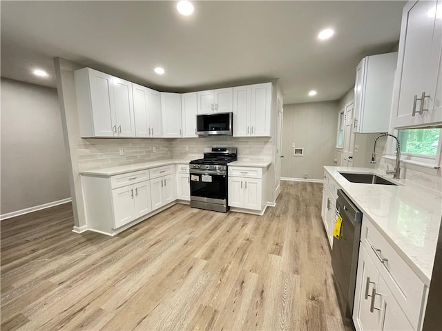 336 Shady Lane Cir, Canton, GA 30115 - kitchen featuring appliances with stainless steel finishes, baseboards, a sink, light wood finished floors, and backsplash