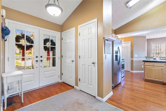 foyer entrance with french doors, light hardwood / wood-style flooring, and lofted ceiling