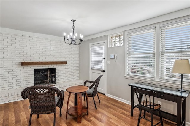 dining area featuring a fireplace, light hardwood / wood-style flooring, and a notable chandelier