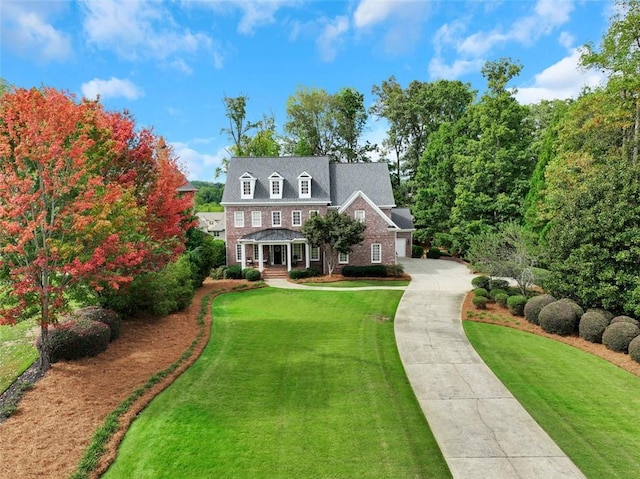 view of front of property featuring driveway, brick siding, and a front yard