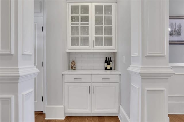 bar with wood finished floors and decorative backsplash