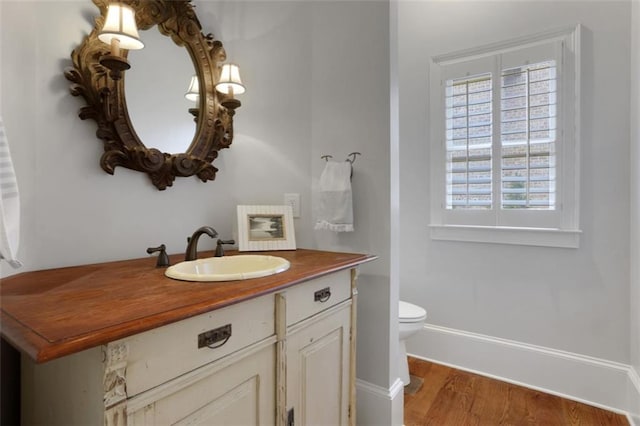 bathroom with wood finished floors, vanity, toilet, and baseboards