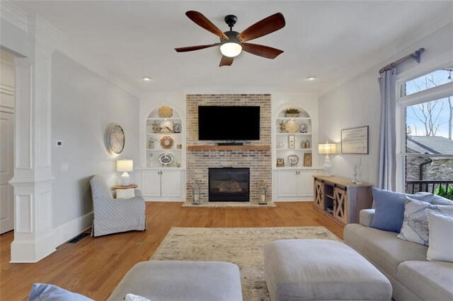 living room featuring ceiling fan, wood finished floors, built in features, and ornate columns