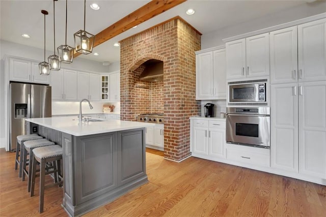 kitchen featuring white cabinets, light wood-style floors, appliances with stainless steel finishes, and a sink
