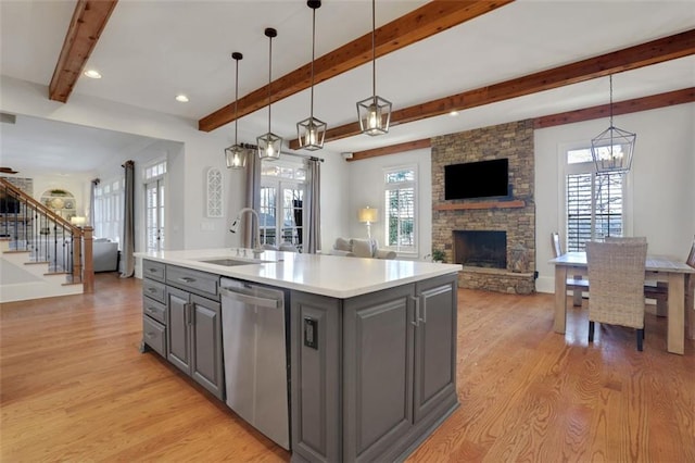 kitchen with light wood-style flooring, a sink, open floor plan, gray cabinetry, and dishwasher
