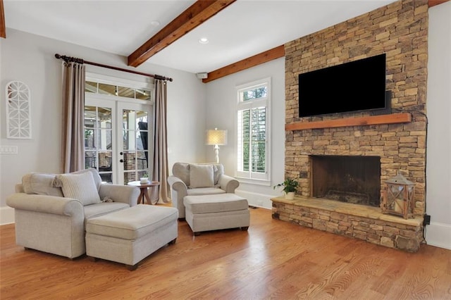 living area featuring french doors, recessed lighting, beamed ceiling, wood finished floors, and a fireplace