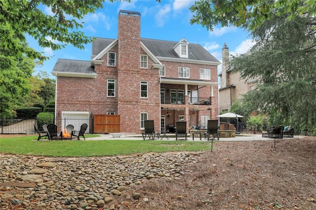 back of property with a fire pit, a chimney, fence, brick siding, and a patio area