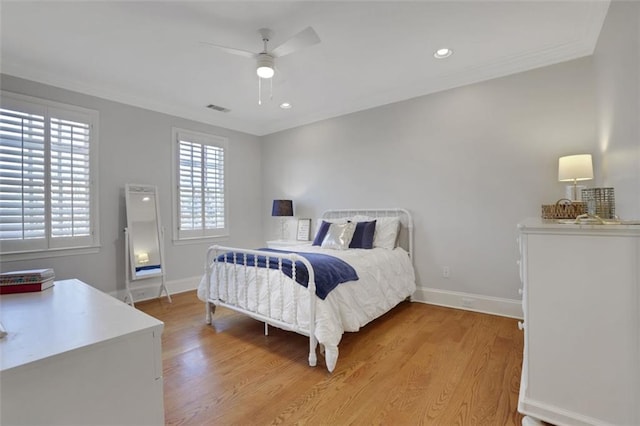 bedroom featuring light wood finished floors, baseboards, visible vents, ceiling fan, and crown molding