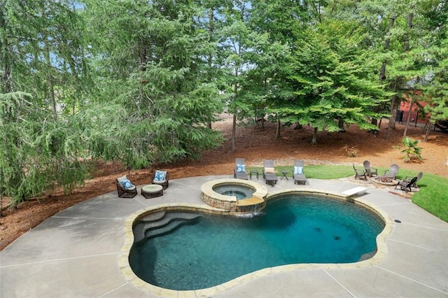 pool with a fire pit, a diving board, a patio area, and an in ground hot tub