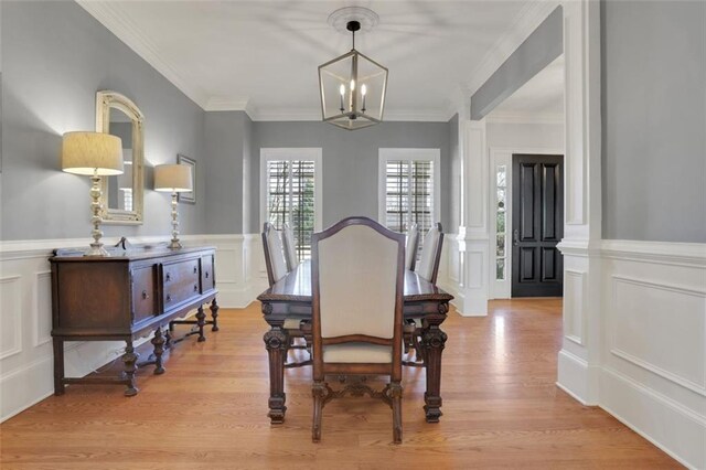 dining area featuring wainscoting, a decorative wall, ornamental molding, and an inviting chandelier