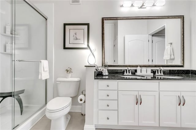 bathroom with an enclosed shower, vanity, toilet, and tile patterned flooring