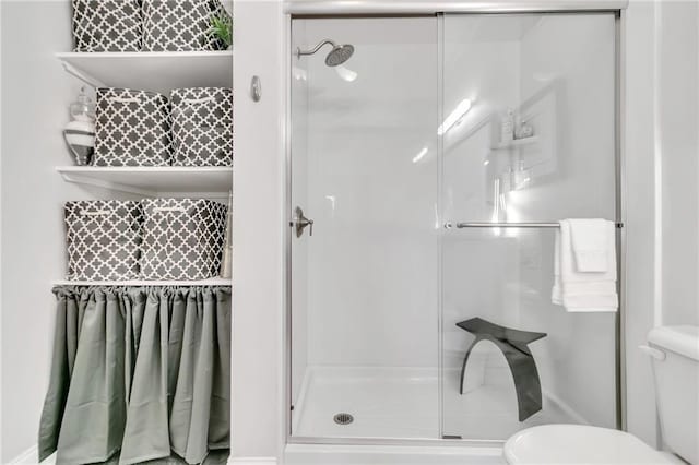 bathroom featuring toilet and a shower with door