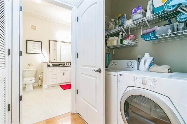 laundry room with light wood-type flooring, separate washer and dryer, and sink