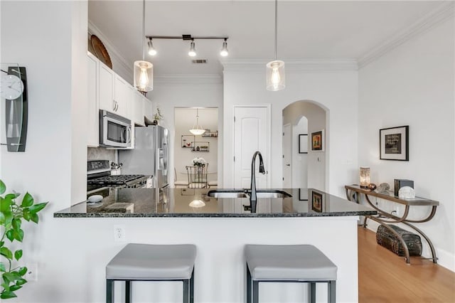 kitchen featuring visible vents, dark stone countertops, appliances with stainless steel finishes, white cabinets, and a sink