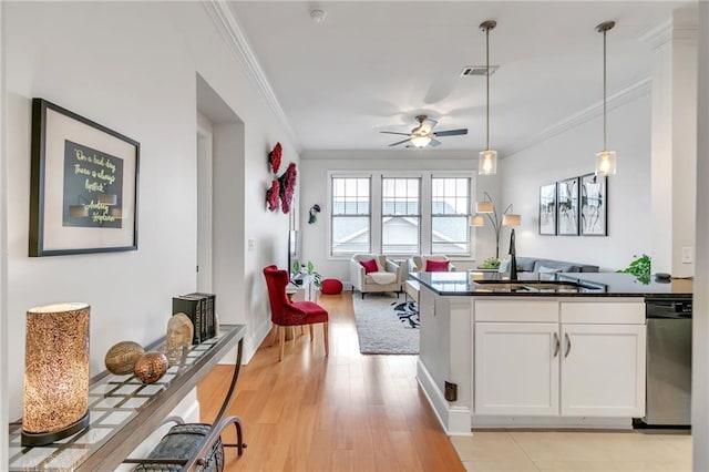 kitchen with light wood-type flooring, ornamental molding, dishwasher, white cabinets, and hanging light fixtures