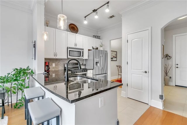 kitchen featuring pendant lighting, light hardwood / wood-style flooring, ornamental molding, white cabinetry, and stainless steel appliances