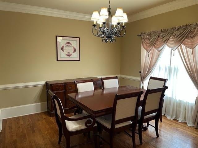 dining space featuring baseboards, ornamental molding, wood finished floors, and an inviting chandelier