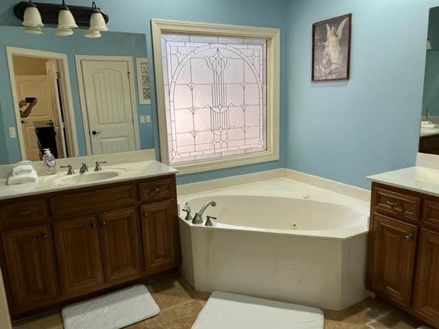 bathroom with a garden tub and vanity