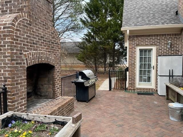 view of patio / terrace featuring an outdoor brick fireplace and a grill