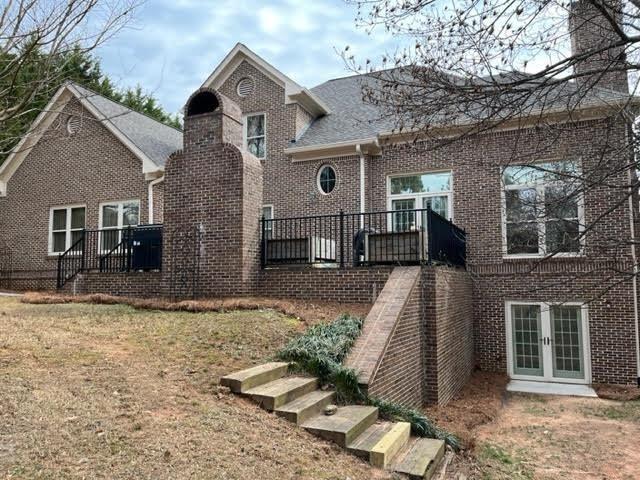 back of house featuring french doors and brick siding