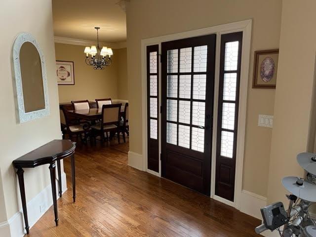 entrance foyer with a healthy amount of sunlight, crown molding, a notable chandelier, and wood finished floors