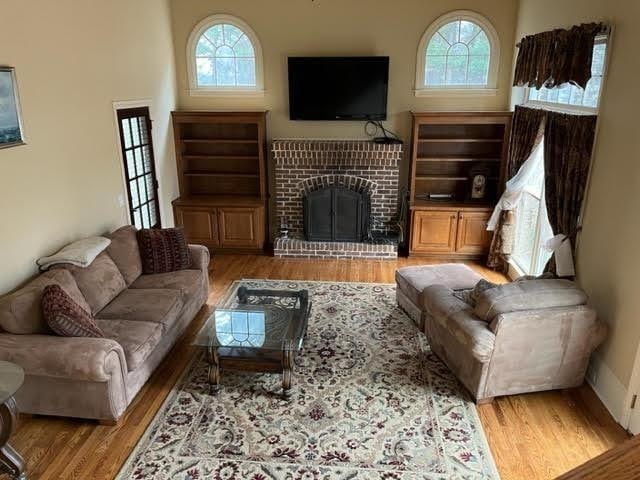 living room featuring a brick fireplace and wood finished floors