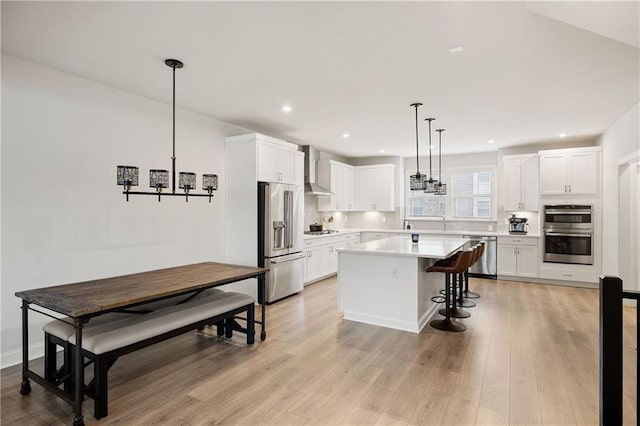 kitchen with a breakfast bar area, stainless steel appliances, light countertops, light wood-style flooring, and white cabinets