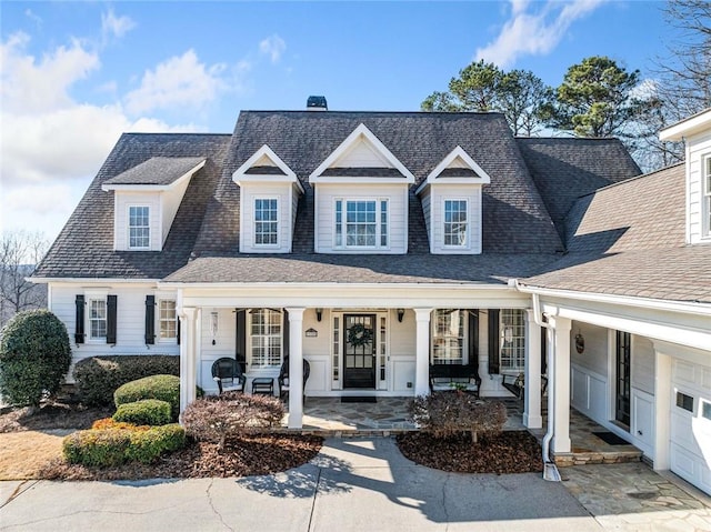 view of front of home with roof with shingles, a porch, and a chimney