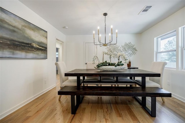 dining room with an inviting chandelier, baseboards, visible vents, and light wood-style floors