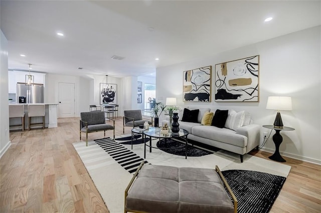 living room featuring light wood-type flooring, baseboards, and recessed lighting