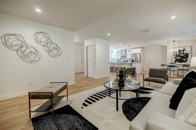 living room with a notable chandelier, light wood-style flooring, recessed lighting, baseboards, and visible vents