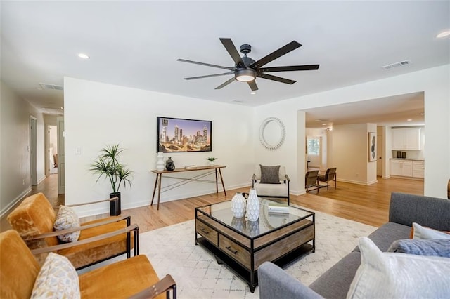 living room with visible vents, baseboards, ceiling fan, light wood-style floors, and recessed lighting