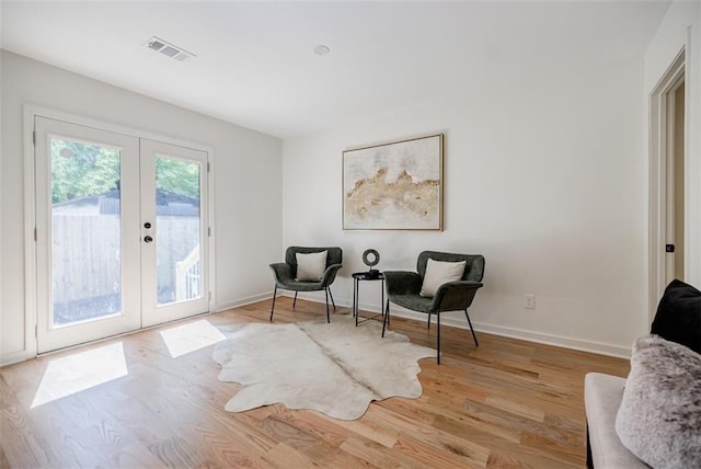 sitting room featuring baseboards, french doors, visible vents, and wood finished floors