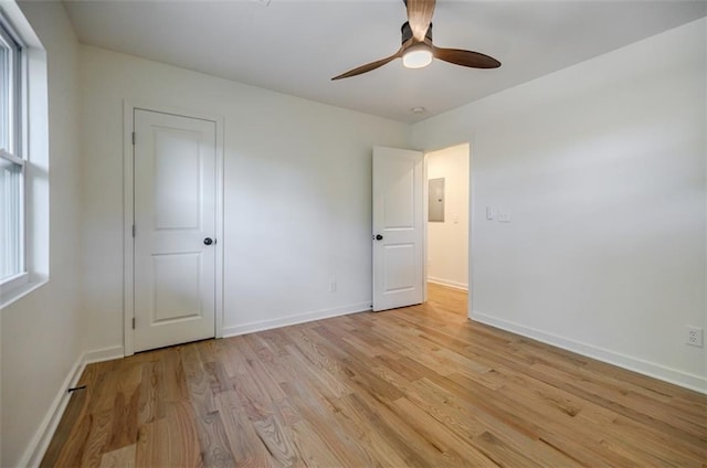 unfurnished bedroom featuring baseboards, light wood-style flooring, a ceiling fan, and electric panel