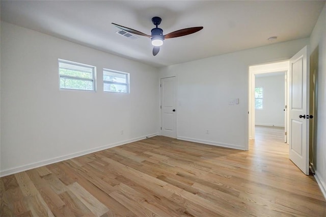 unfurnished room featuring baseboards, light wood finished floors, ceiling fan, and visible vents