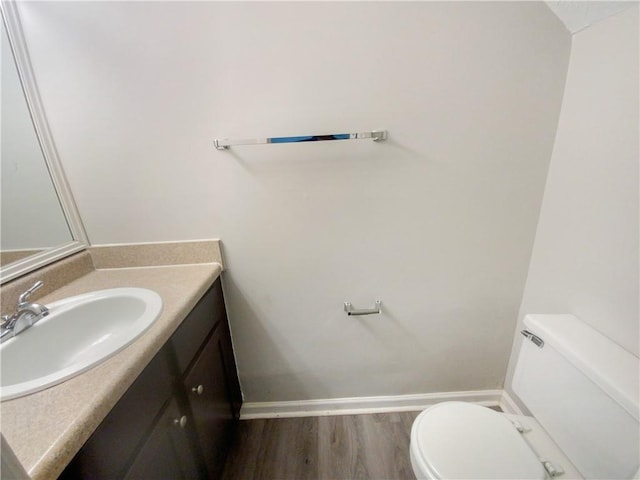 bathroom with toilet, vanity, and hardwood / wood-style flooring