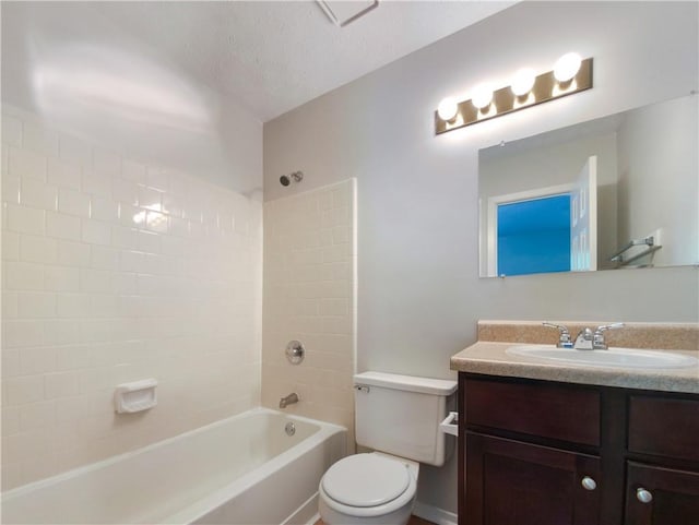 full bathroom featuring toilet, tiled shower / bath combo, a textured ceiling, and vanity