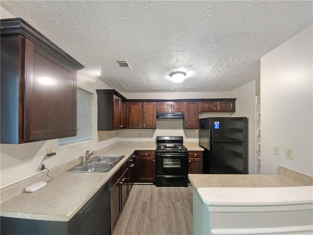 kitchen with a textured ceiling, sink, light hardwood / wood-style floors, black appliances, and dark brown cabinetry