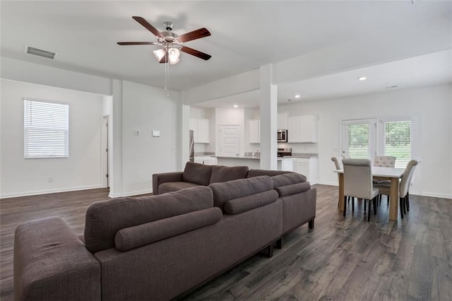 living room featuring ceiling fan and dark hardwood / wood-style flooring