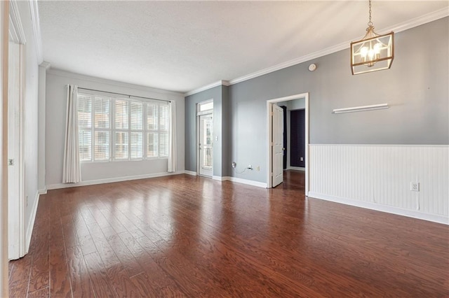 unfurnished room featuring dark wood-style floors, baseboards, crown molding, and an inviting chandelier