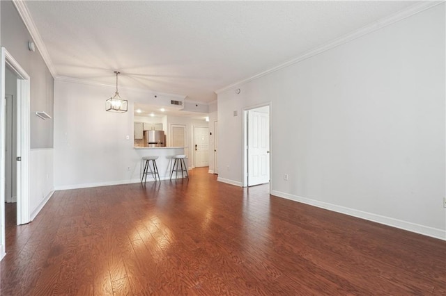 unfurnished living room featuring dark wood-type flooring, an inviting chandelier, and crown molding