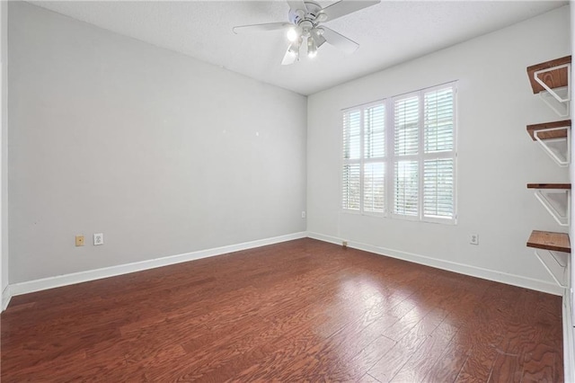 spare room with dark wood-type flooring, baseboards, and a ceiling fan